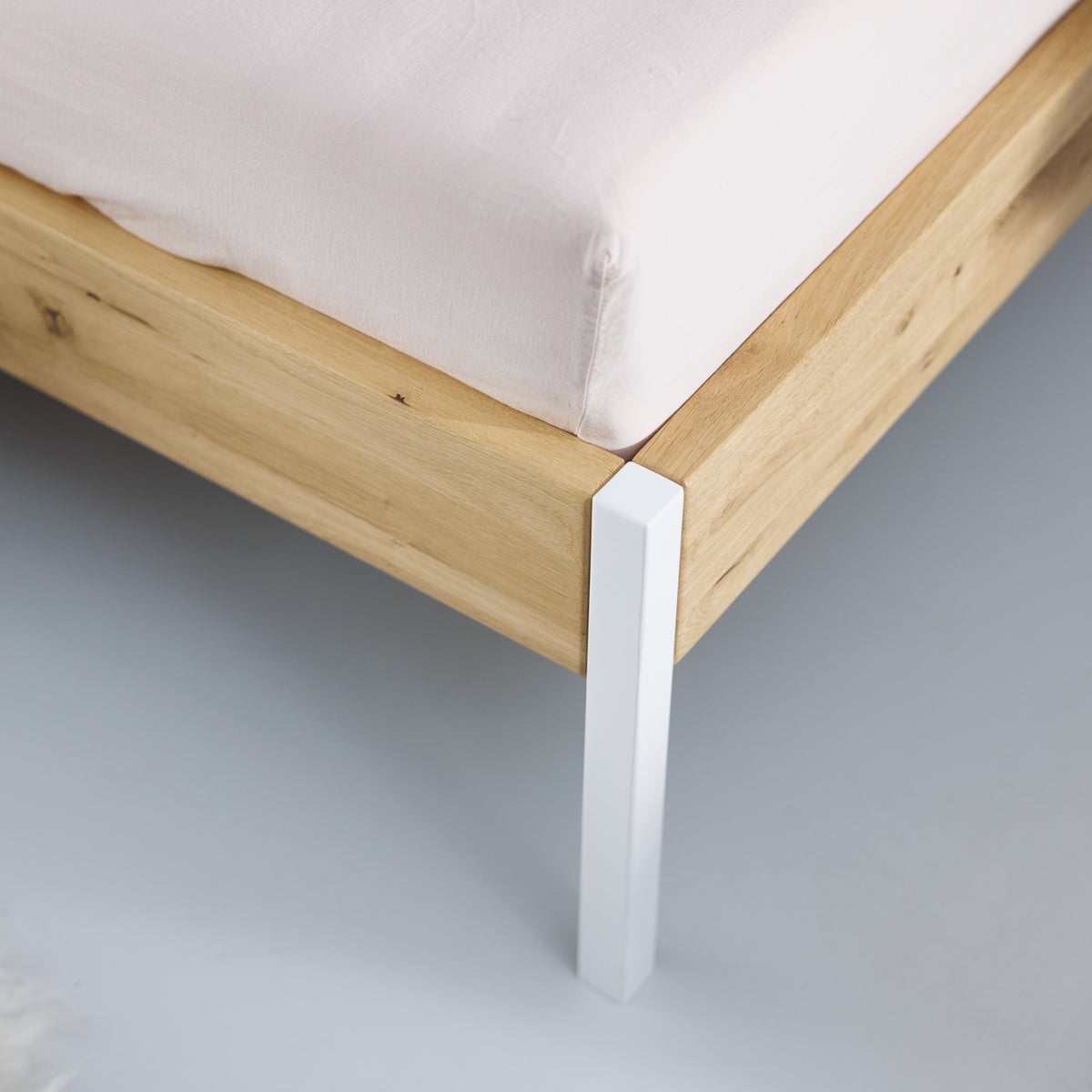 Zeitloses Bett Massivholz mit weißen Metallbeinen - Detailansicht